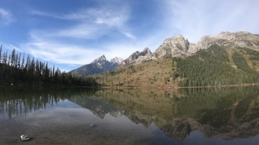 Ośnieżone szczyty pasma Teton odbite w spokojnej tafli String Lake w Parku Narodowym Grand Teton