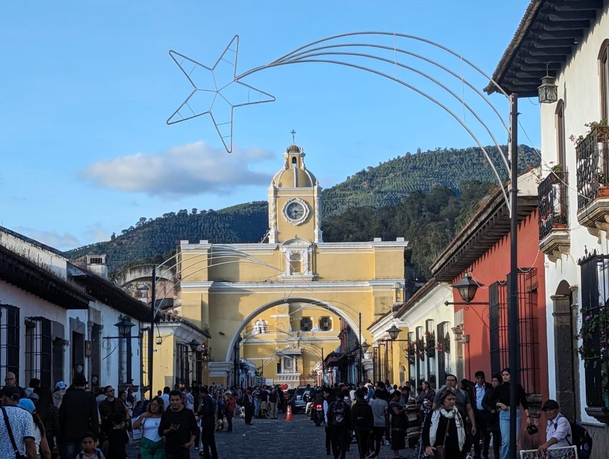 Łuk Arco de Santa Catalina w świątecznych dekoracjach i tłum spacerowiczów na ulicy w Antigua Guatemala