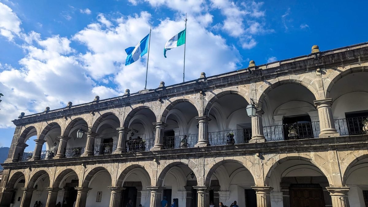 Dwupiętrowe arkady kolonialnego pałacu z flagami Gwatemali w Antigua Guatemala
