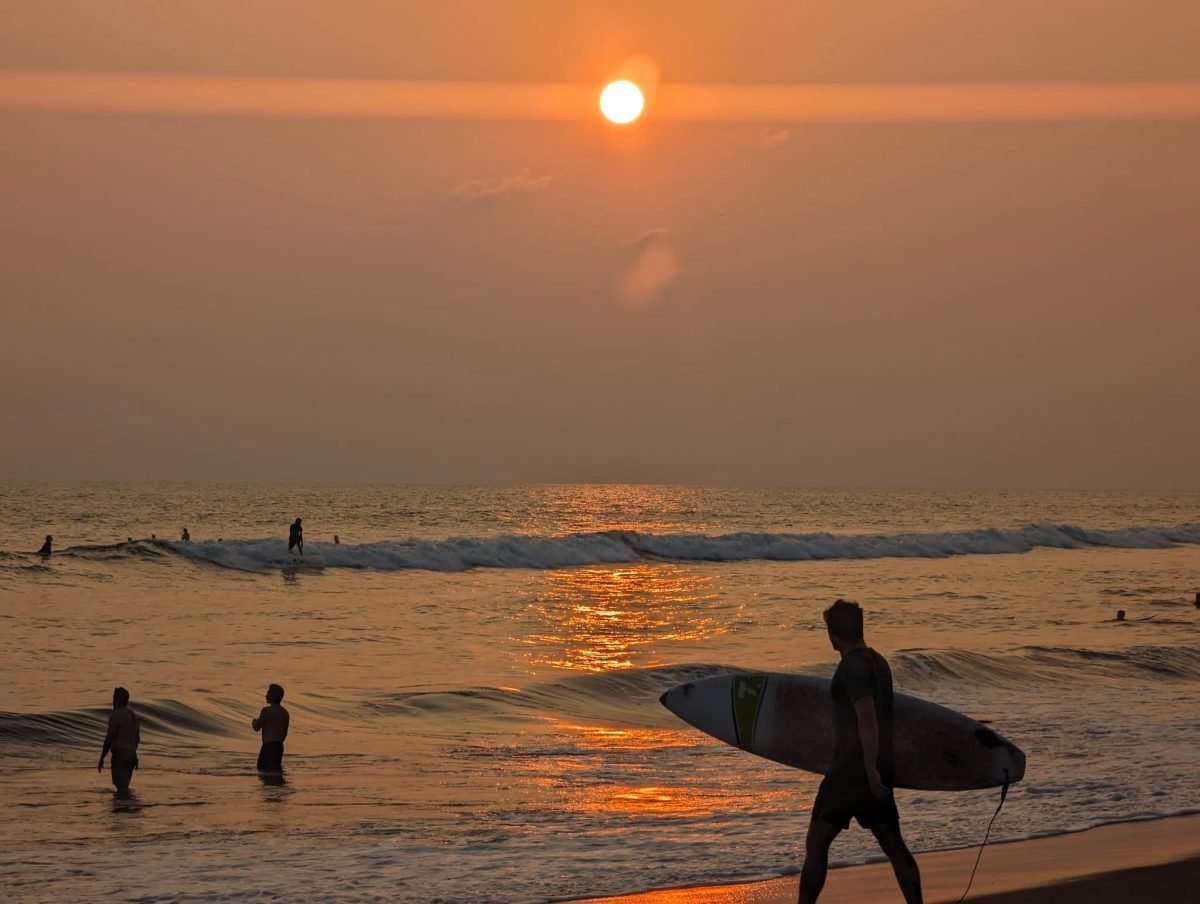 Zachód słońca nad Pacyfikiem i surfer z deską na plaży w El Paredón