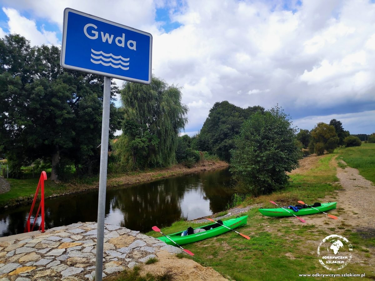 Tablica „Gwda” i kajaki na brzegu na początku spływu przy Gwdzie Wielkiej