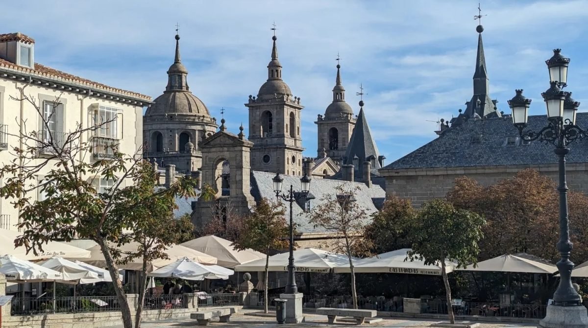 Klasztor-pałac El Escorial z kopułą i wieżami, na pierwszym planie plac z kawiarniami