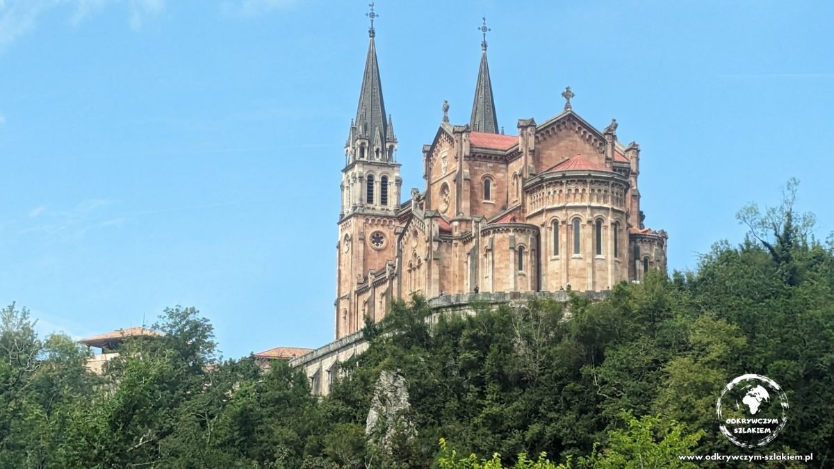 Różowa bazylika Santa María la Real de Covadonga wśród zieleni
