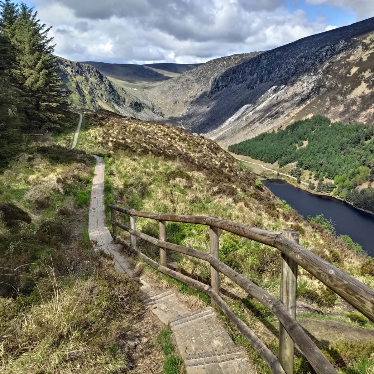Drewniana kładka szlaku nad doliną z jeziorem Upper Lake w Glendalough