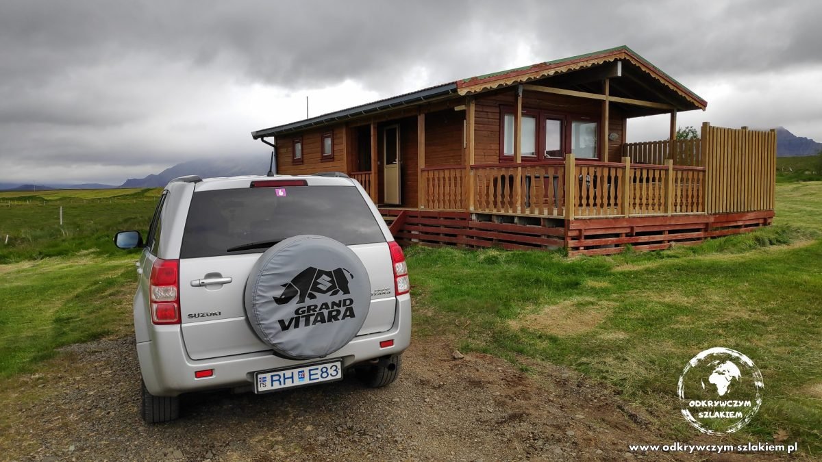 Wynajęte auto 4x4 przed drewnianym domkiem na farmie Snorrastaðir