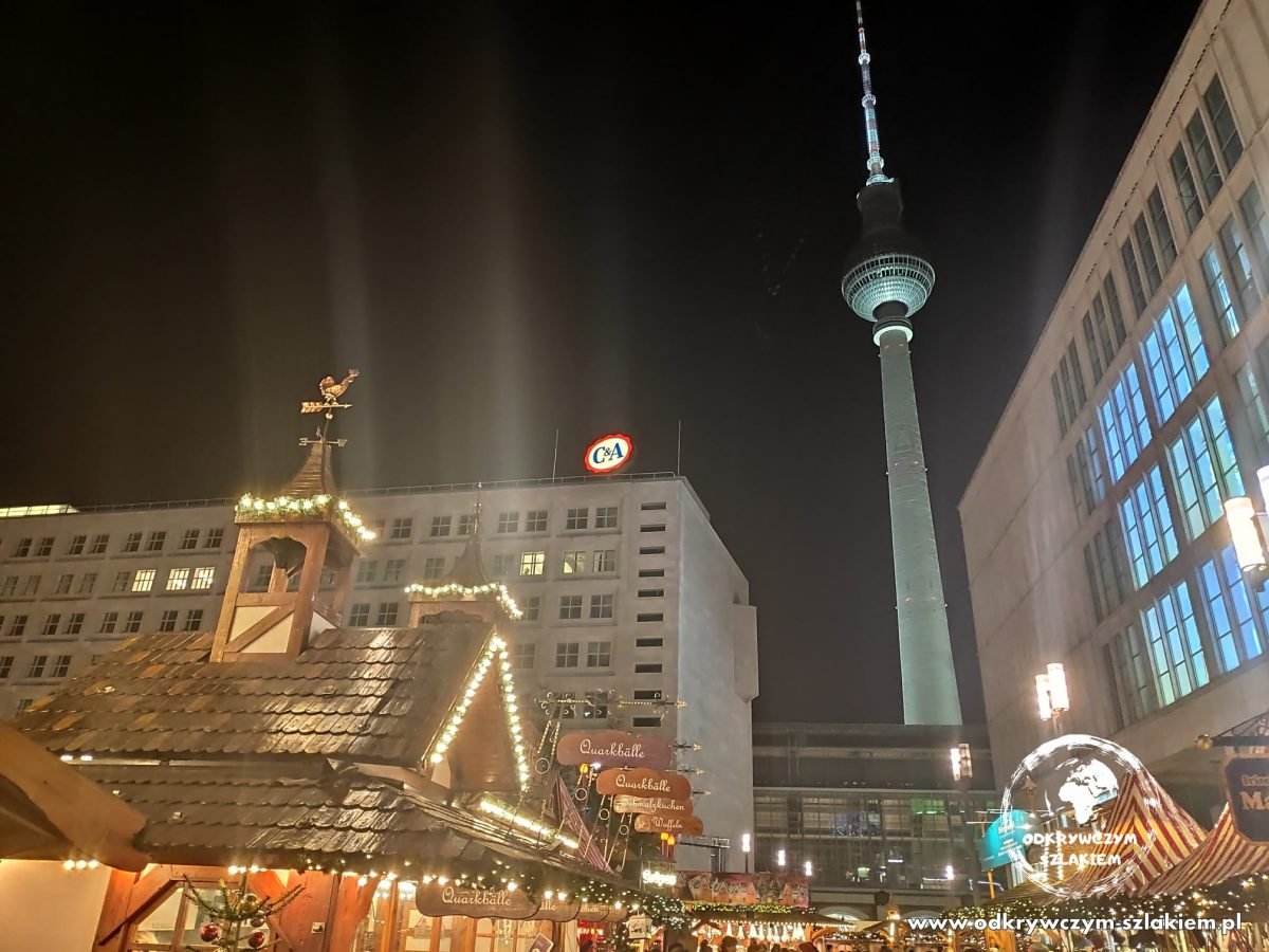 Drewniane budki jarmarku świątecznego przy Alexanderplatz, w tle wieża telewizyjna Fernsehturm