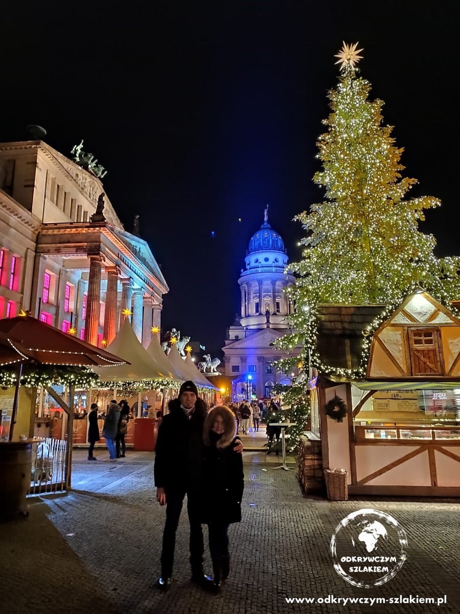 Przy wysokiej choince na jarmarku na Gendarmenmarkt, w tle kopuła Französischer Dom