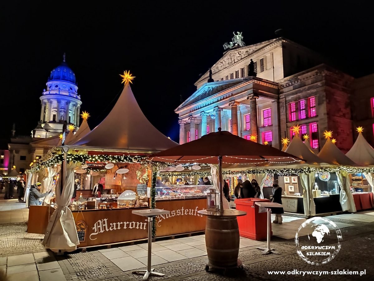 Białe namioty jarmarku na Gendarmenmarkt, w tle podświetlony Konzerthaus i Deutscher Dom