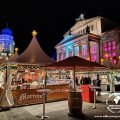 Białe namioty jarmarku na Gendarmenmarkt, w tle podświetlony Konzerthaus i Deutscher Dom