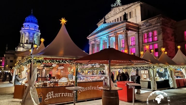 Białe namioty jarmarku na Gendarmenmarkt, w tle podświetlony Konzerthaus i Deutscher Dom