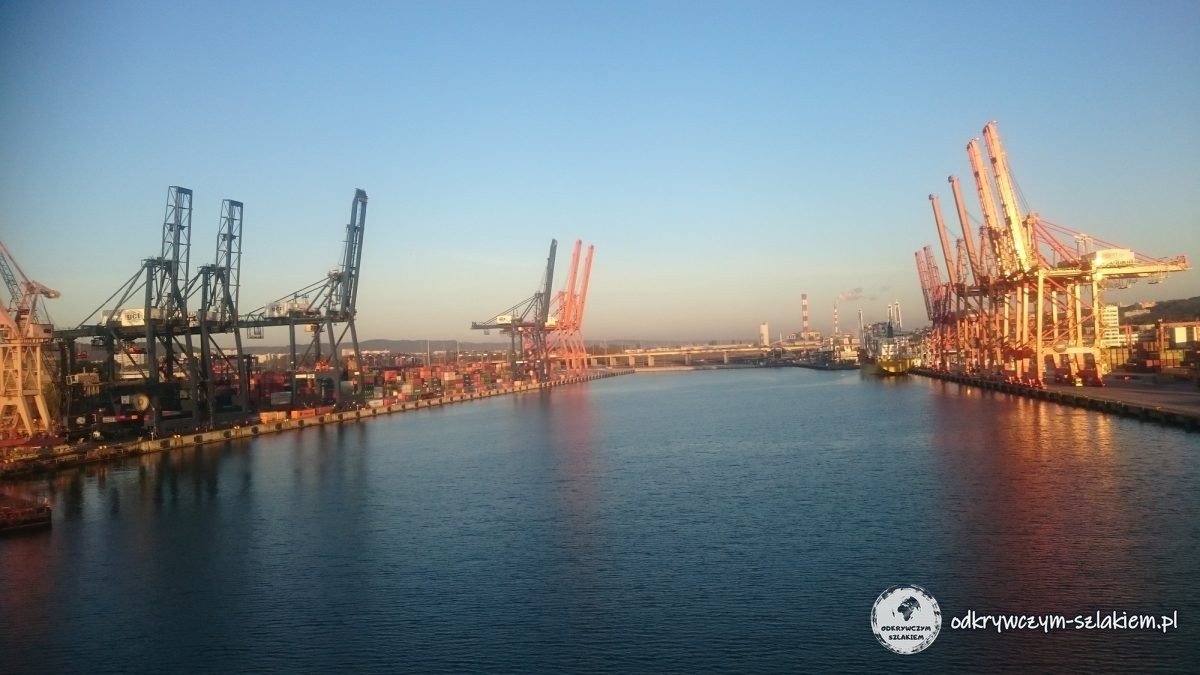Grúas de la terminal de contenedores a ambos lados del canal del puerto de Gdynia al amanecer, vistas desde el ferry