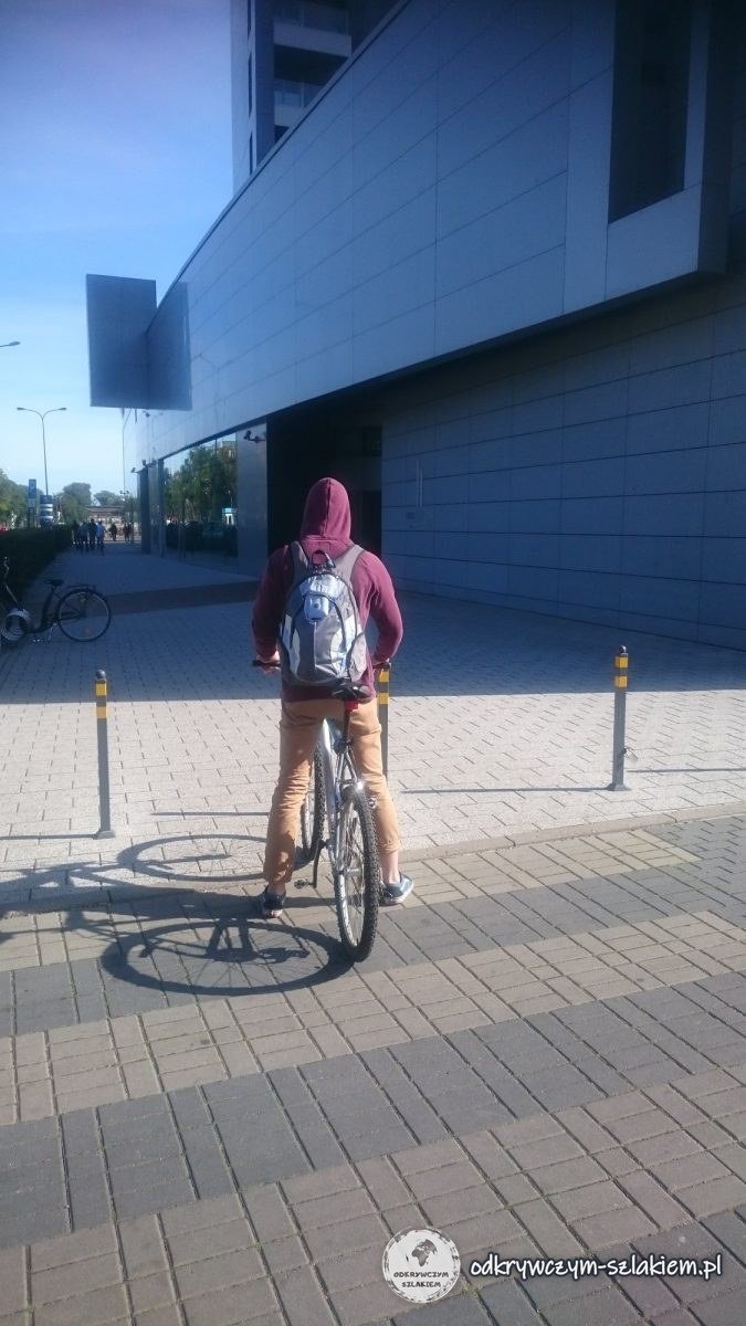 Un ciclista con sudadera granate y mochila en la entrada de las Sea Towers de Gdynia