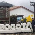Maciek przy dużym napisie BOGOTA na szczycie Monserrate, obok drogowskaz do kolejek
