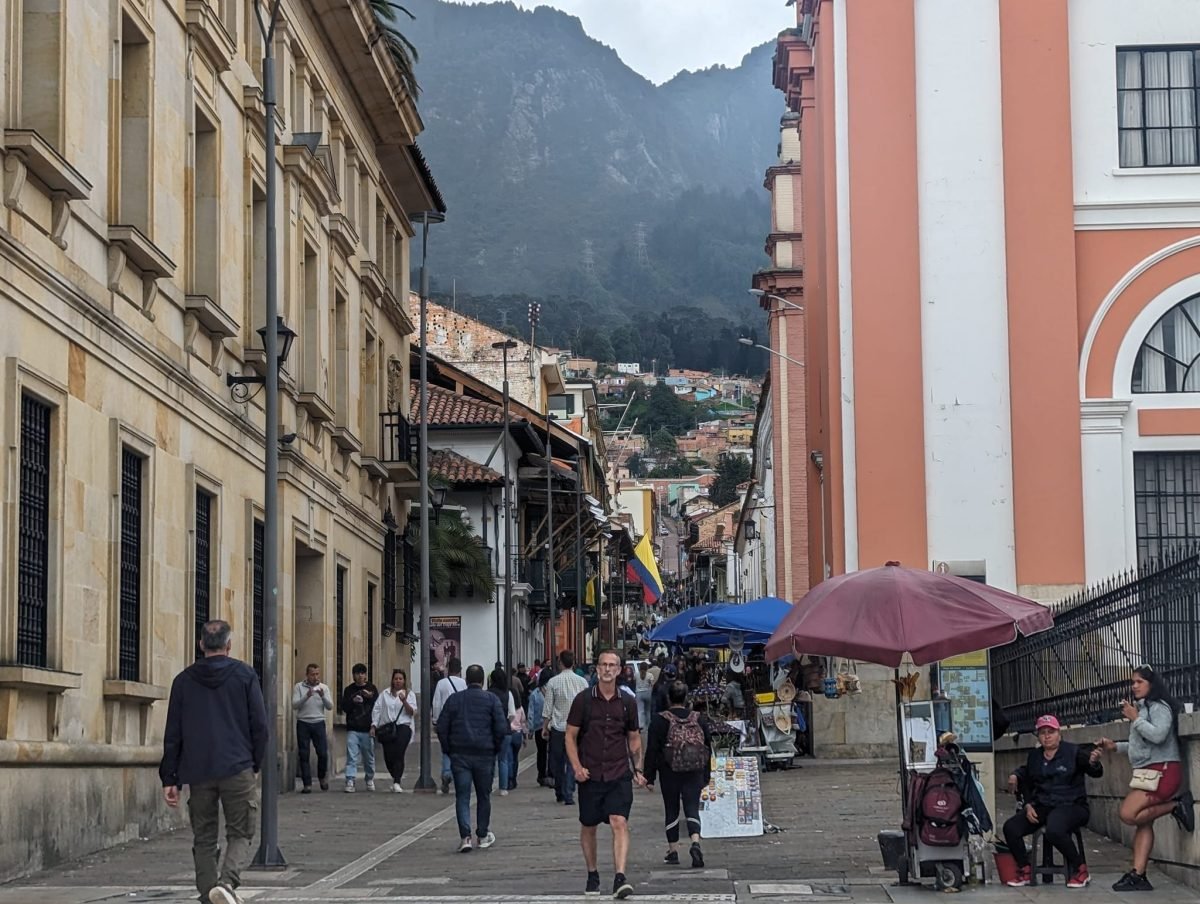 Ulica w La Candelarii w Bogocie z zalesionymi górami w tle i spacerowiczami na chodniku