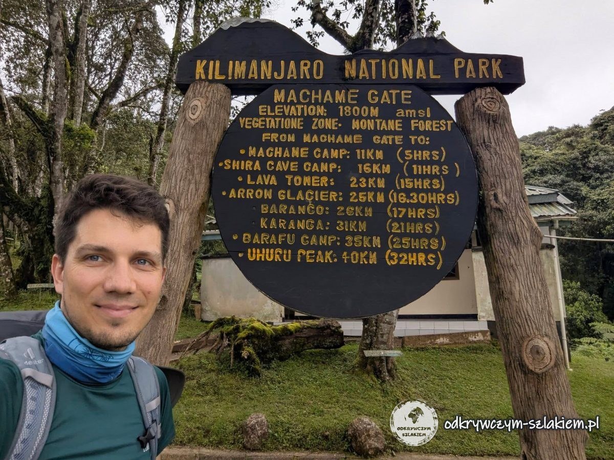 Maciek przy tablicy Machame Gate (1800 m n.p.m.) z odległościami do obozów i Uhuru Peak