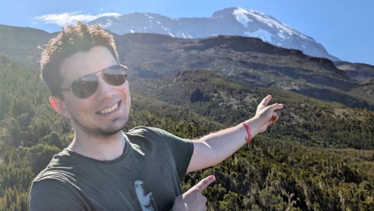 Maciek wskazuje ośnieżony szczyt Kibo na Kilimandżaro z wrzosowisk powyżej Machame Camp