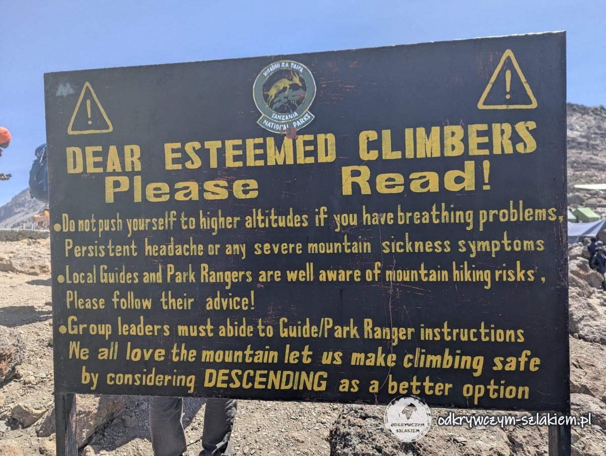 Tablica „Dear esteemed climbers – please read” z ostrzeżeniem przed chorobą wysokościową przy Barafu Camp