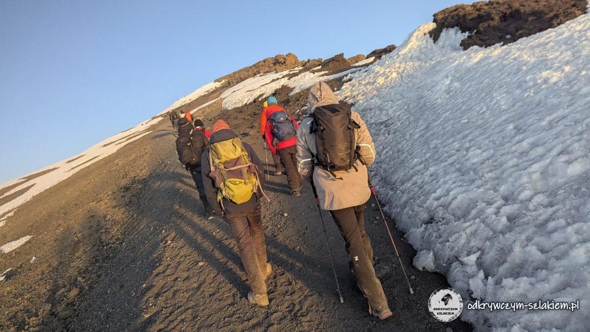 Uczestnicy wyprawy na ścieżce wzdłuż zmrożonego śniegu w drodze na Uhuru Peak