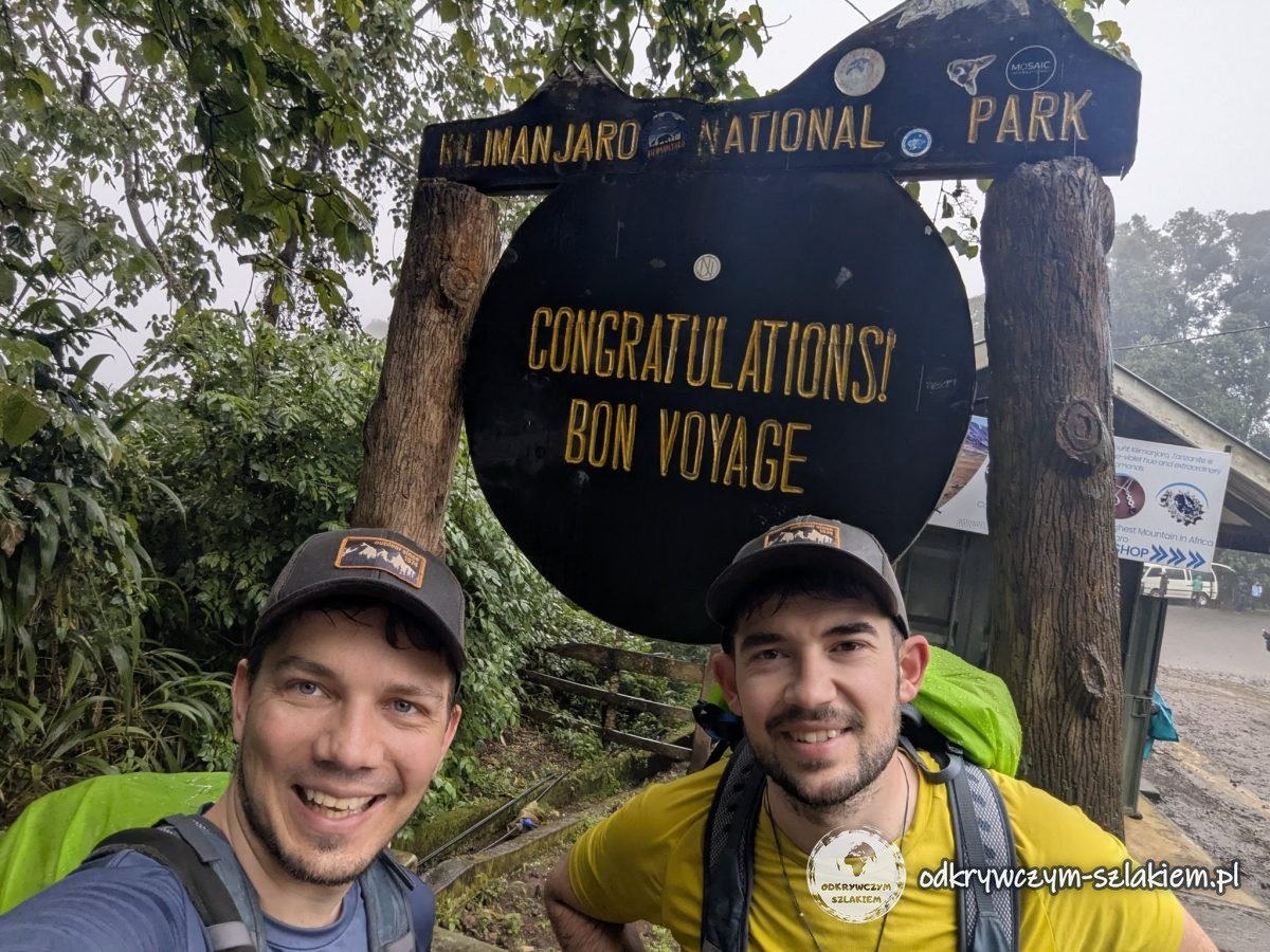 Z Michałem przy tablicy „Congratulations! Bon voyage” przy Mweka Gate