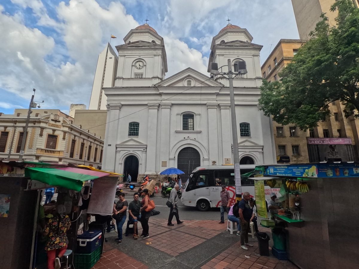 Biały kościół z dwiema wieżami w centrum Medellín i uliczne stragany z owocami