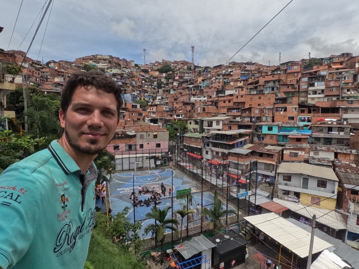 Maciek nad boiskiem do koszykówki w Comuna 13, w tle zabudowa na zboczu