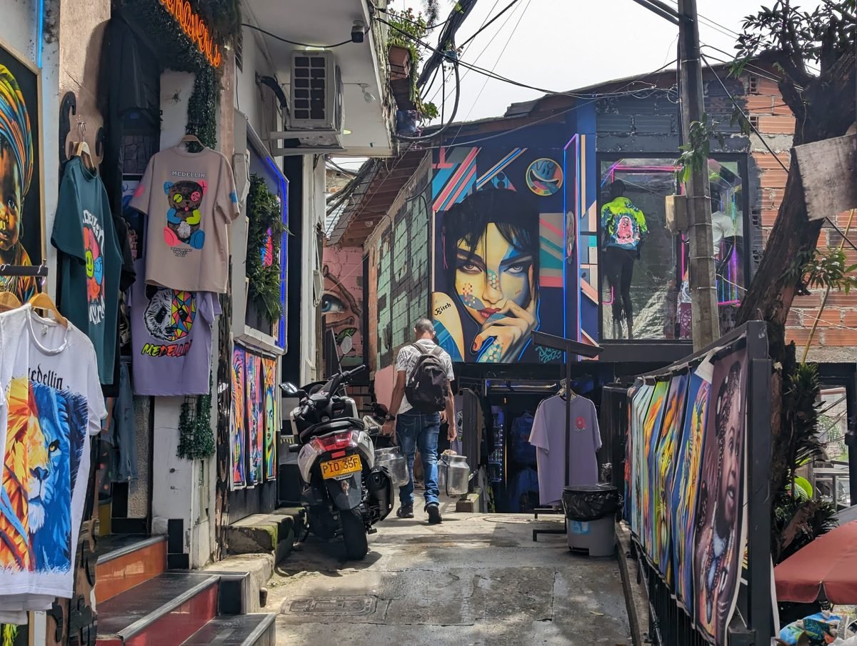 Uliczka w Comuna 13 z koszulkami z napisem Medellín, obrazami i muralem kobiety