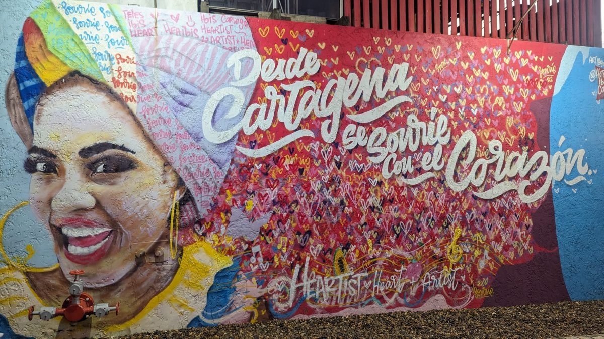 Mural z uśmiechniętą kobietą i napisem Desde Cartagena na ścianie w Kartagenie