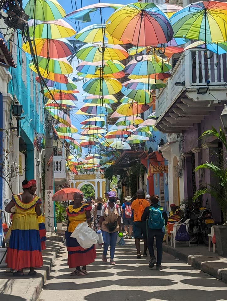 Palenquera w kolorowej sukni pod parasolkami na uliczce w Getsemaní