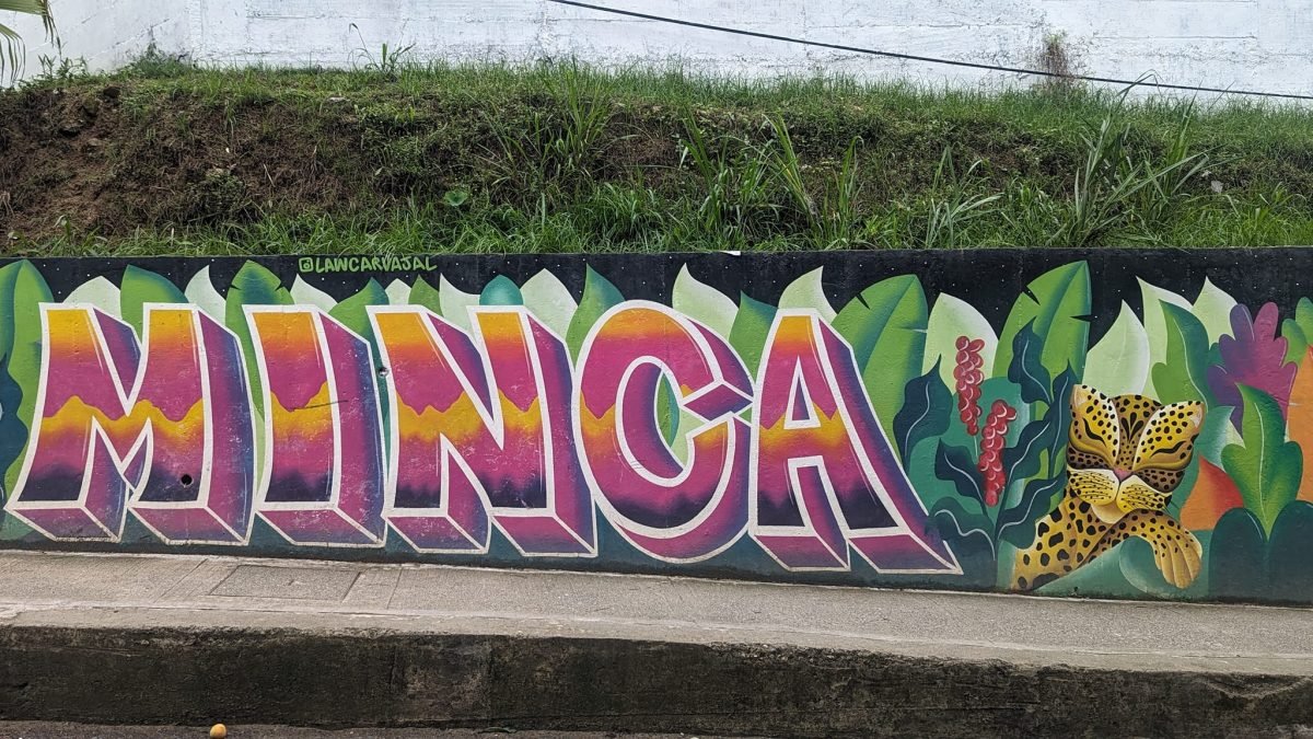 Kolorowy mural z napisem Minca na murku przy drodze do miasteczka