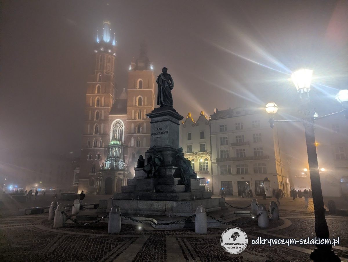 El monumento a Adam Mickiewicz y la basílica de Santa María entre la niebla de noche