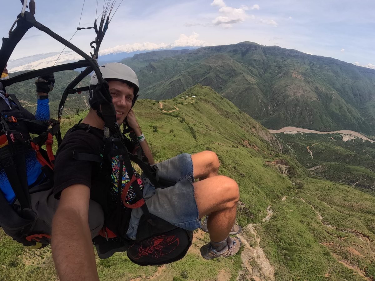 Maciek w uprzęży podczas lotu paralotnią nad zielonymi zboczami kanionu Chicamocha