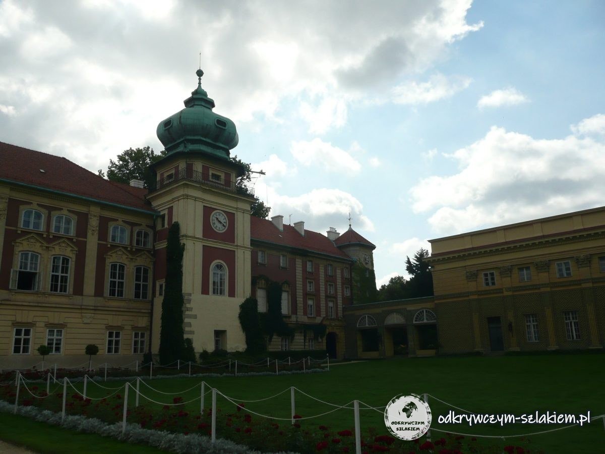 Fachada del castillo de Łańcut con una torre del reloj de chapitel verde sobre el césped