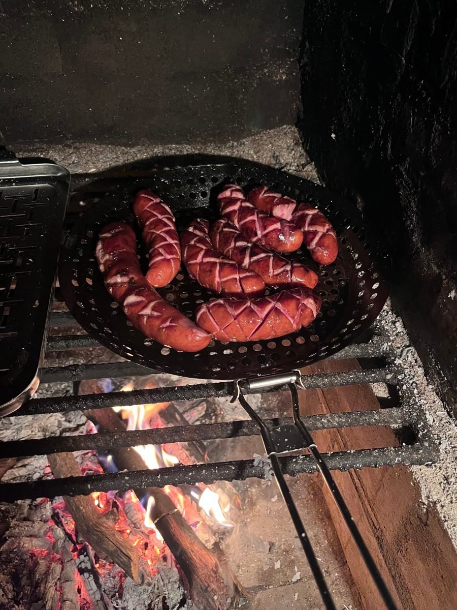Kiełbaski w koszu grillowym nad żarem podczas wieczoru po rajdzie