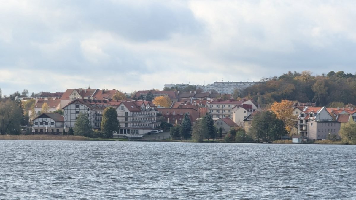 Mrągowo widziane znad jeziora Czos, kamienice i jesienne drzewa na wzgórzu