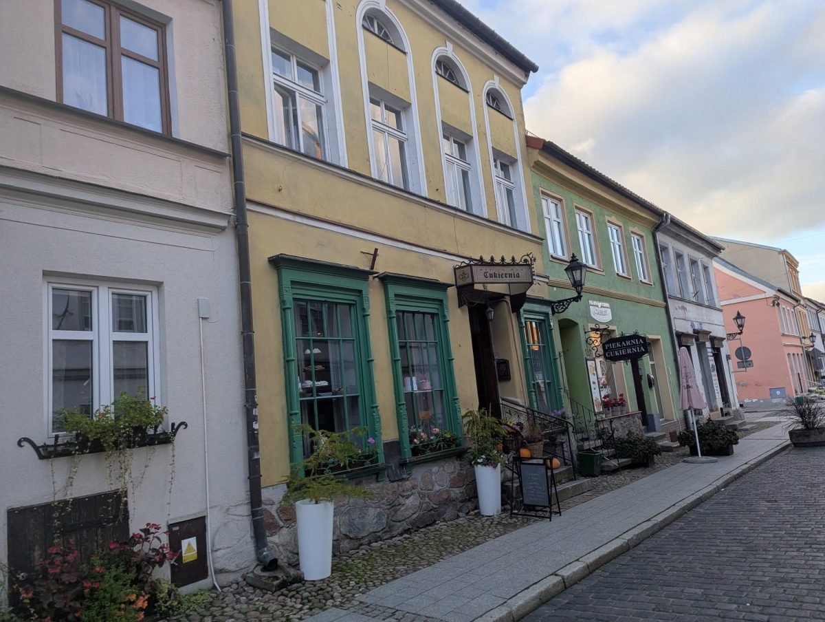 Kolorowe kamienice z kwiatami w oknach przy brukowanej ulicy w Reszlu