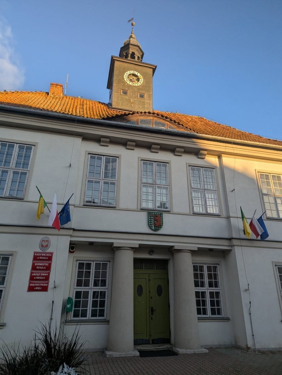 Ratusz z wieżyczką zegarową i flagami w Reszlu