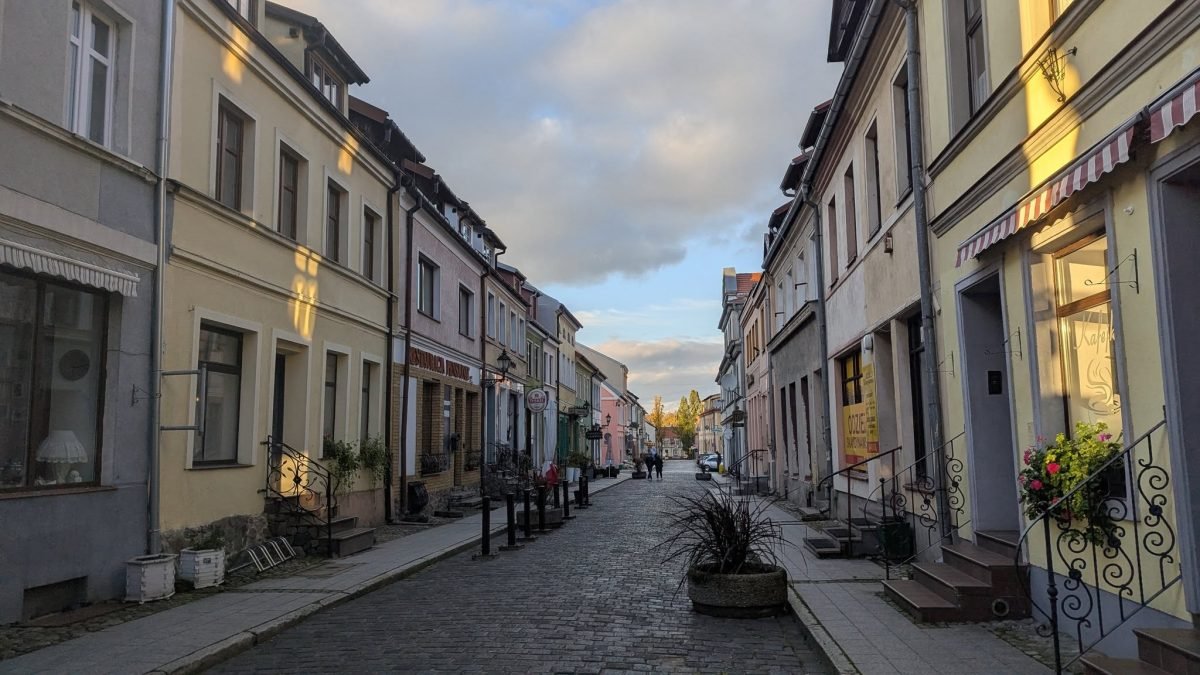 Brukowana uliczka z niskimi kamienicami na starym mieście w Reszlu