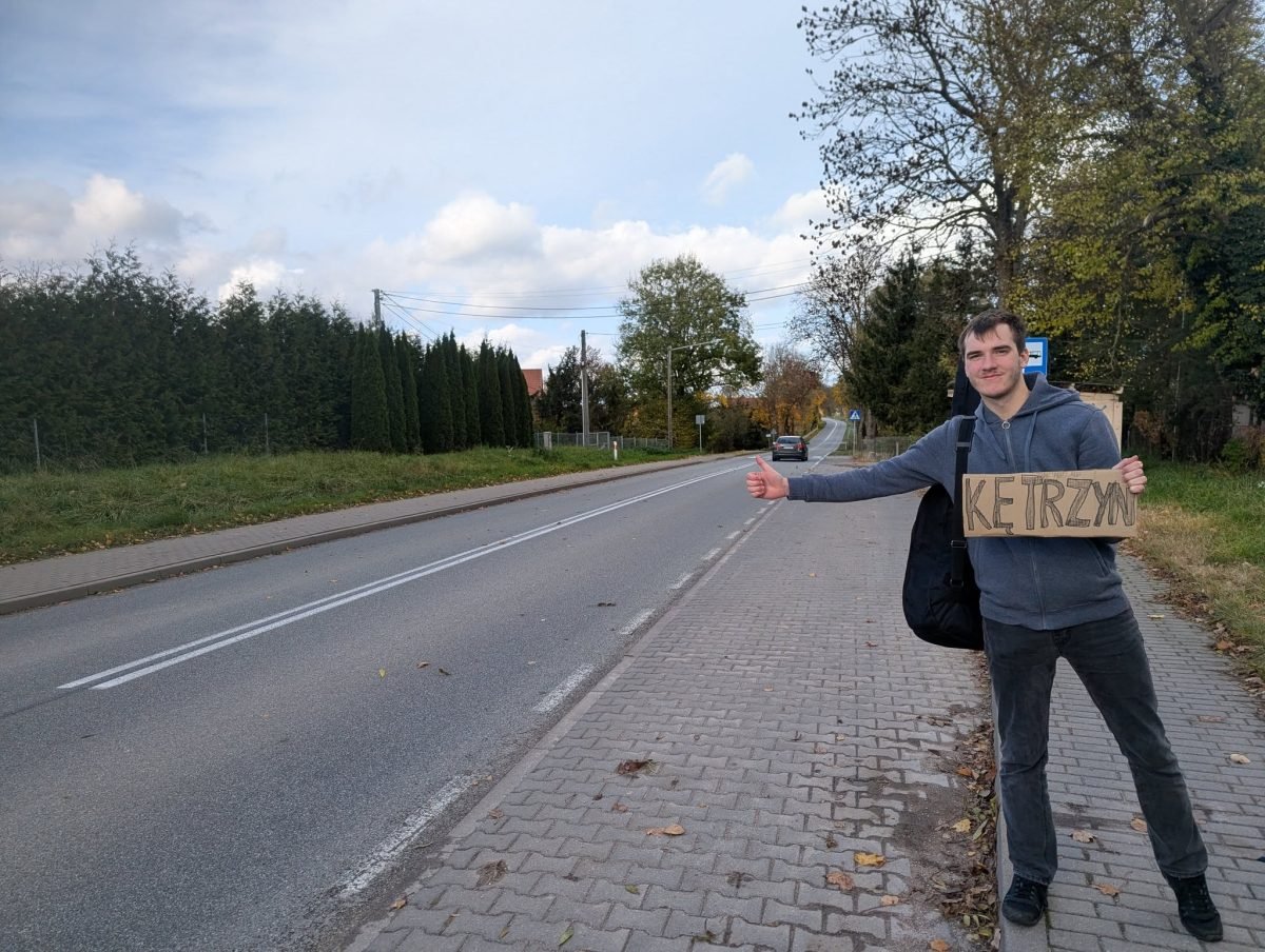Łapanie stopa z tabliczką „Kętrzyn” przy drodze wylotowej z Mrągowa