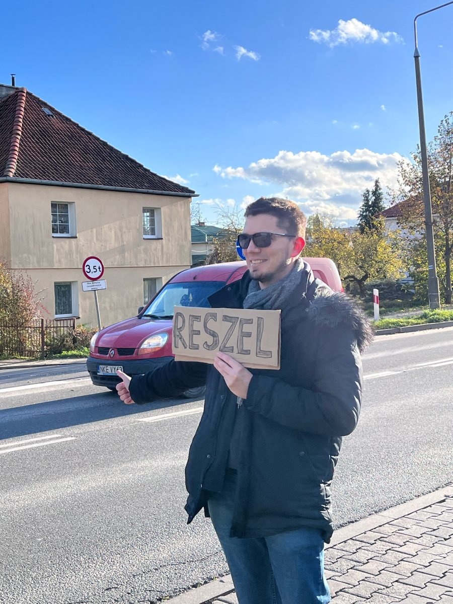Łapanie stopa z tabliczką „Reszel” przy ulicy w Kętrzynie