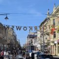 Piotrkowska Street in Łódź in summer – the sign above the promenade, colourful tenements with flowers and crowds of walkers