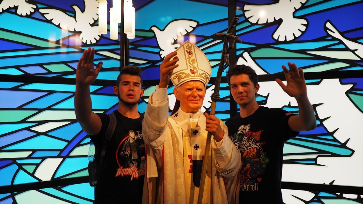 Figura woskowa papieża Jana Pawła II na tle witrażu z gołębiami – Madame Tussauds Berlin