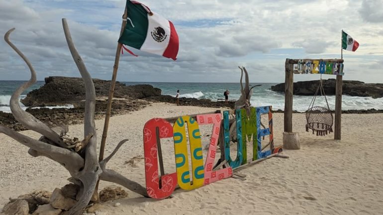 Kolorowy napis „Cozumel” i meksykańskie flagi na plaży na wschodnim wybrzeżu wyspy