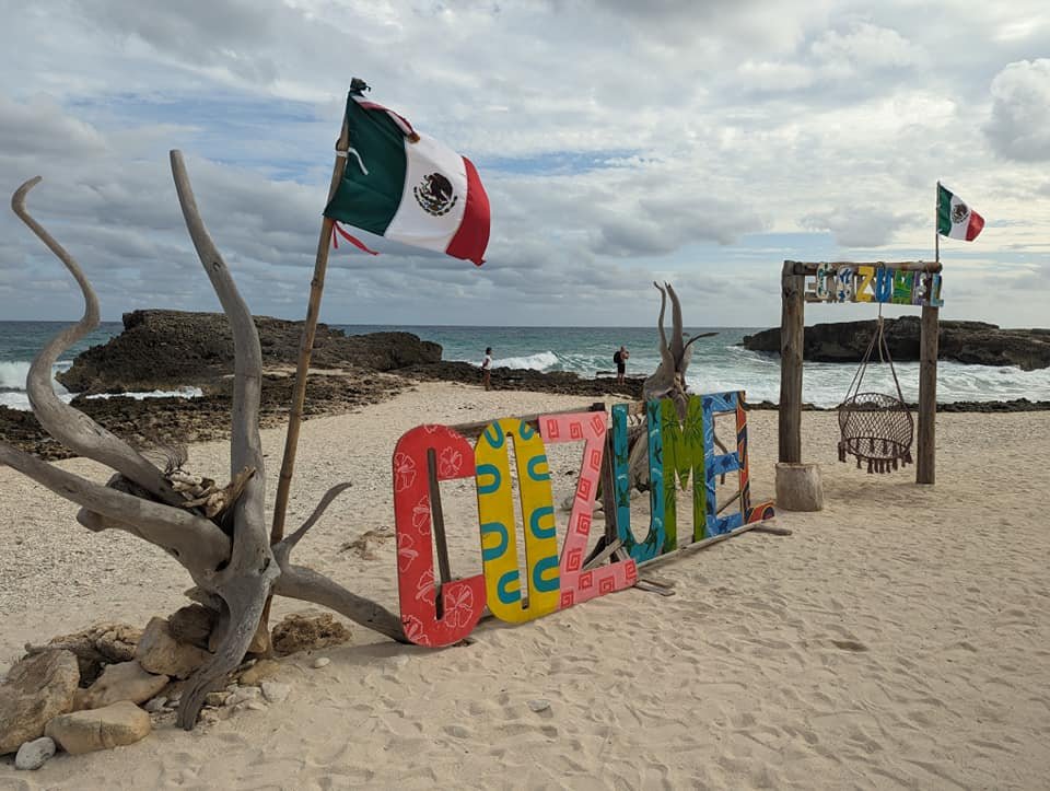 Kolorowy napis „Cozumel” i meksykańskie flagi na plaży na wschodnim wybrzeżu wyspy