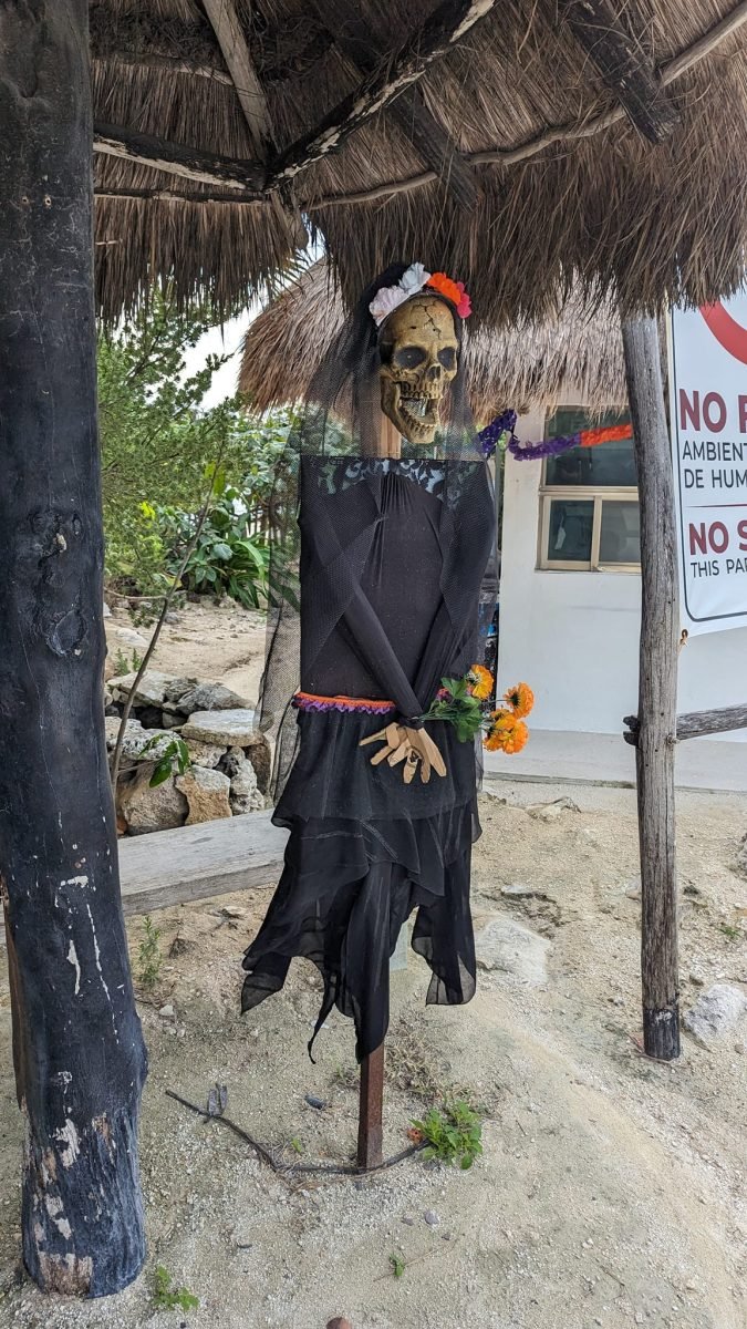 Figura szkieletu w czarnym stroju pod daszkiem z liści palmowych przy plaży na Cozumel