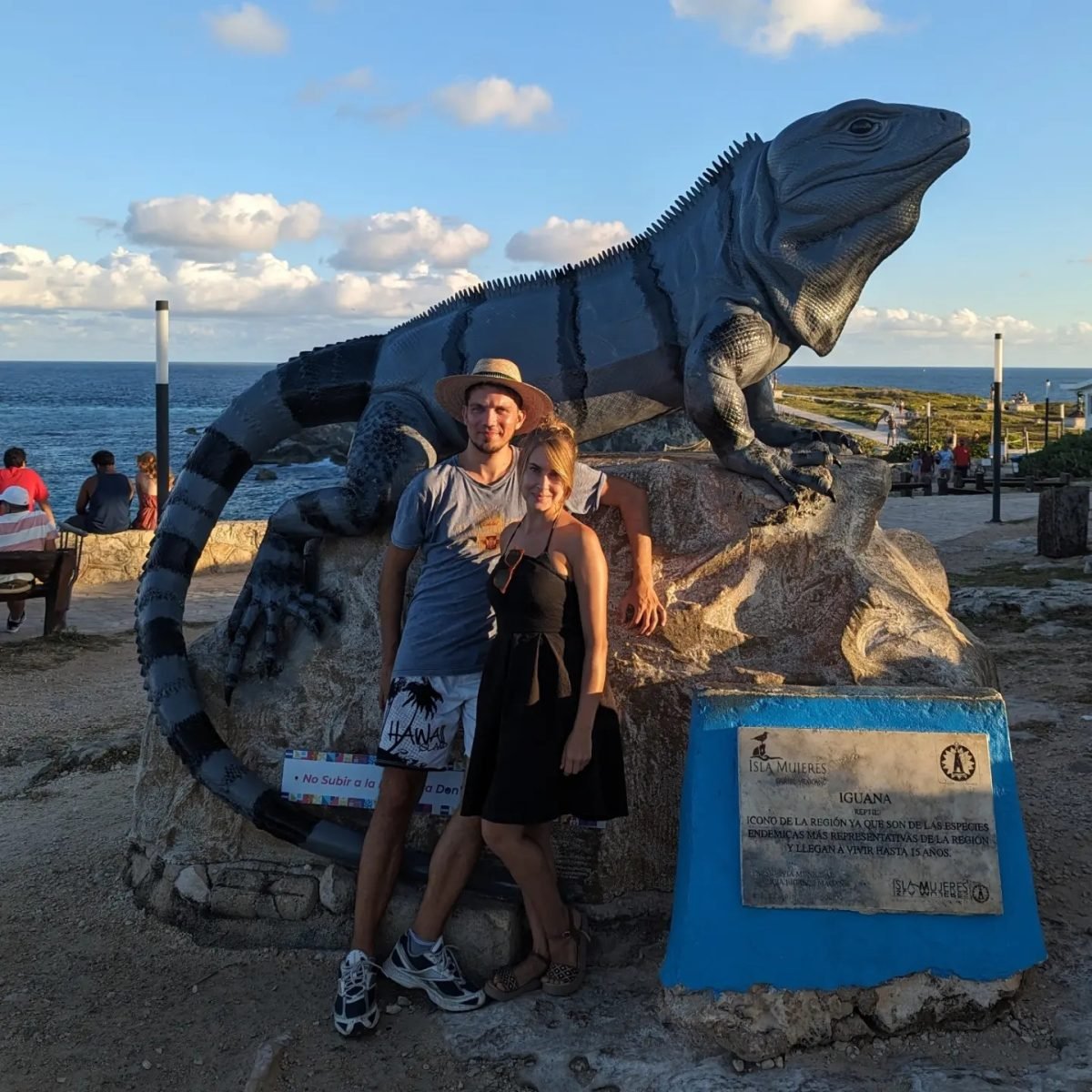 Przy dużej rzeźbie legwana nad brzegiem morza na Isla Mujeres