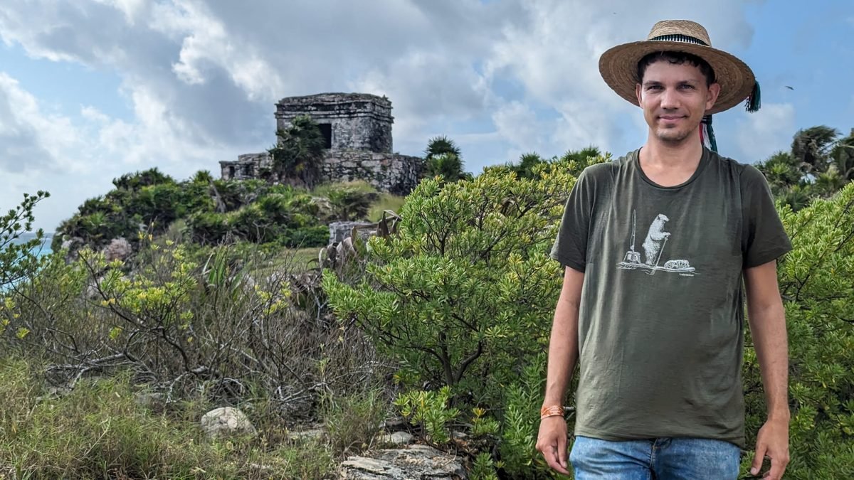 W kapeluszu przed ruinami Tulum, w tle świątynia El Castillo na klifie