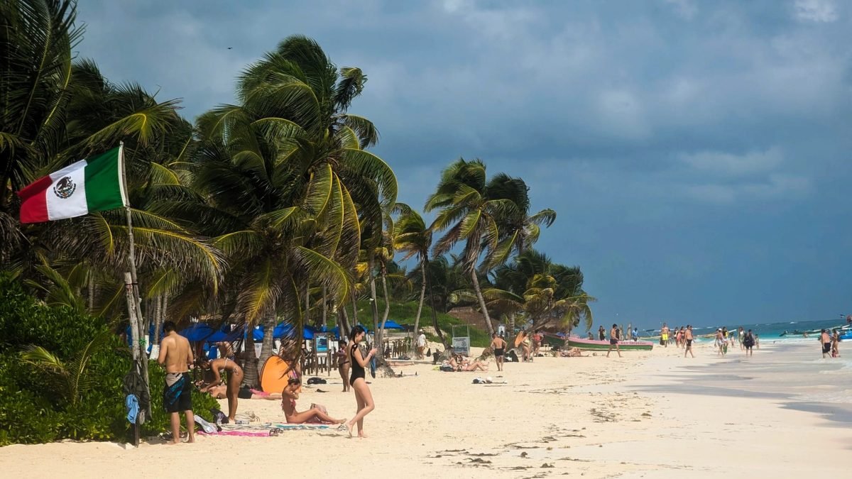 Publiczna plaża w Tulum z meksykańską flagą i palmami