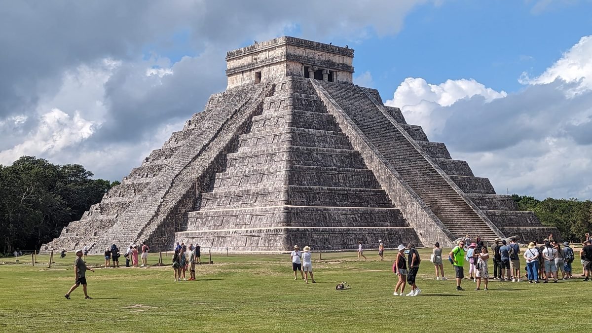 Piramida Kukulkana na Wielkim Placu w Chichén Itzá i zwiedzający na trawie