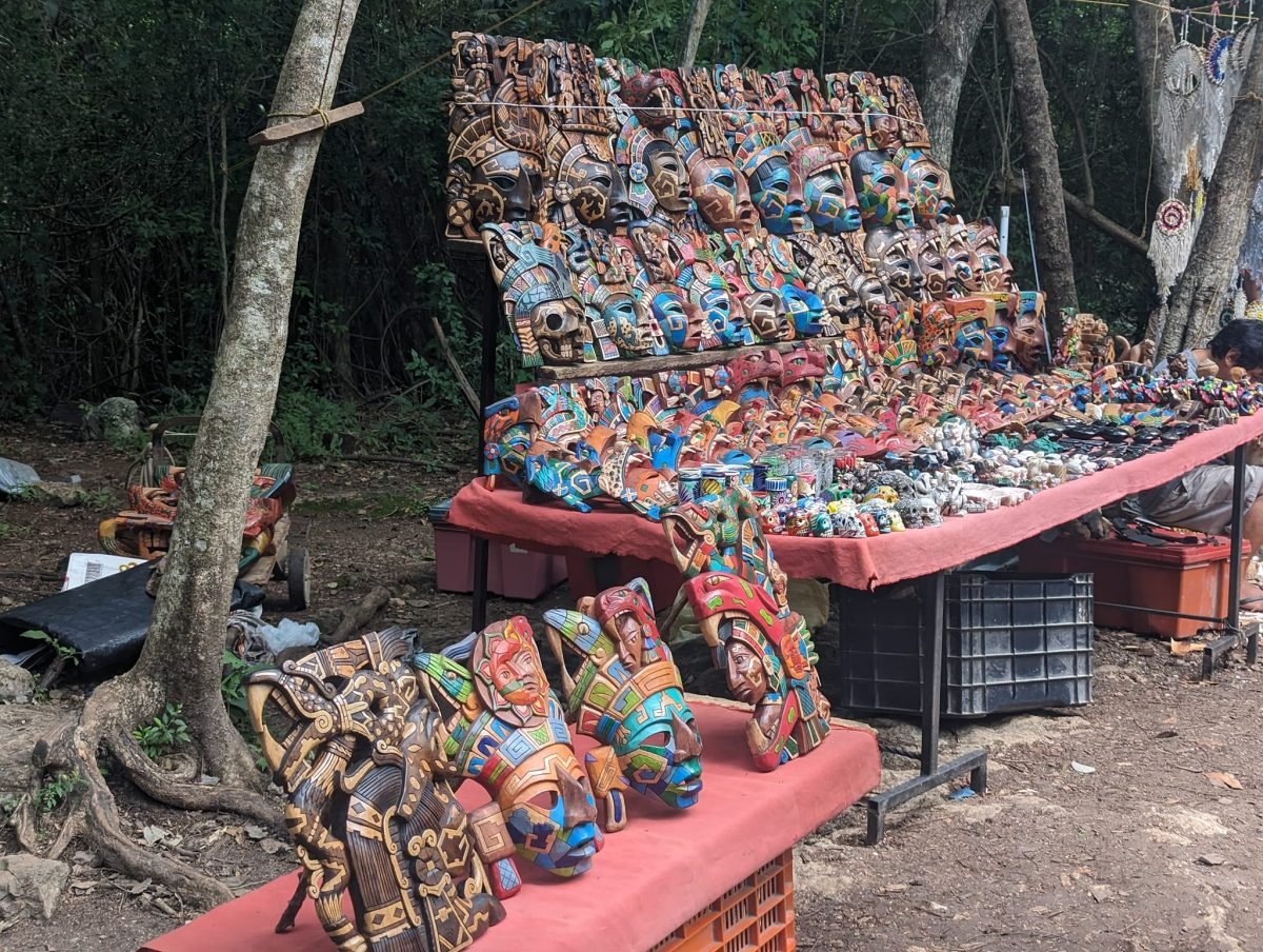 Stragany z kolorowymi maskami i pamiątkami przy alejkach w Chichén Itzá