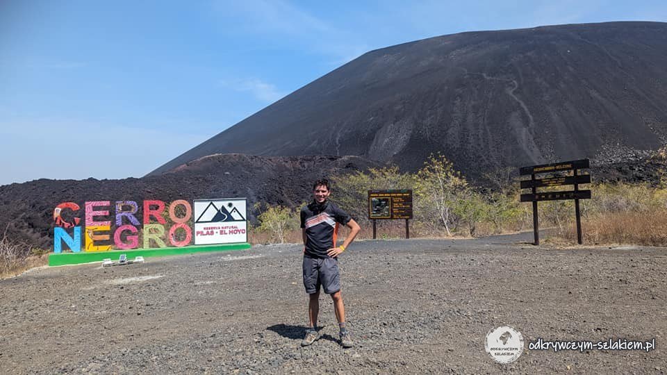Maciek przy kolorowym napisie Cerro Negro u stóp czarnego wulkanu